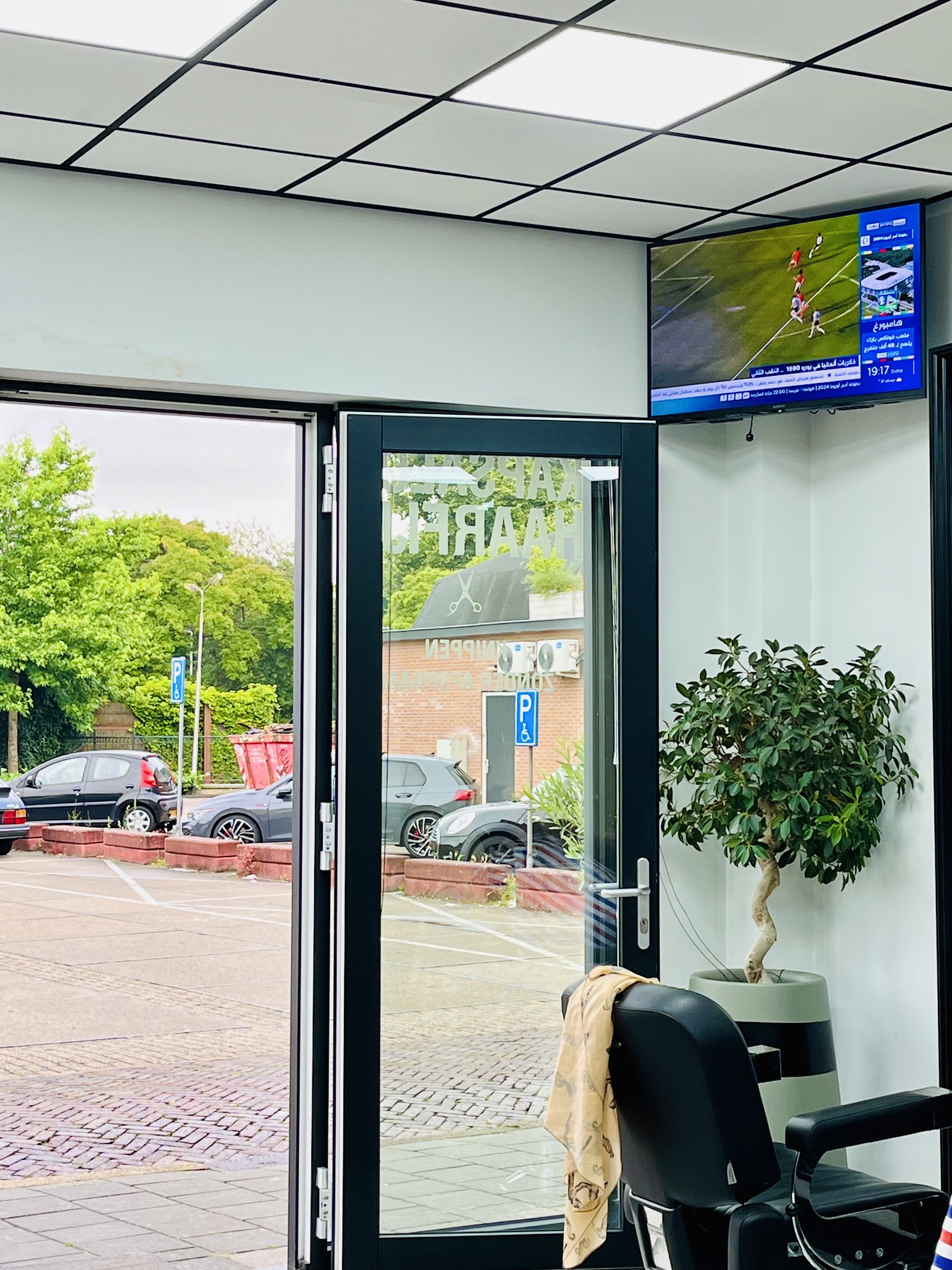 De entree van Haarfijn met een kappersstoel en uitzicht op de Veldweg